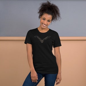K&ouml;nnte beinhalten: Schwarzes T-Shirt mit detaillierter Illustration einer Fledermaus im Flug. Das Design ist in einer hellen Farbe gehalten und mittig auf der Brust platziert. Das T-Shirt hat einen klassischen Rundhalsausschnitt.