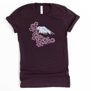 May include: A dark purple t-shirt with a white graphic of Mount Fuji and pink cherry blossoms.