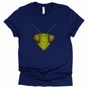 May include: A navy blue t-shirt with a green praying mantis face graphic. The mantis has large, round eyes and a detailed illustration.