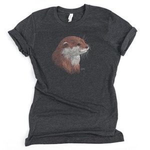 May include: A dark heather grey t-shirt with a detailed illustration of an otter's head. The otter is facing right and has a brown and white fur pattern.
