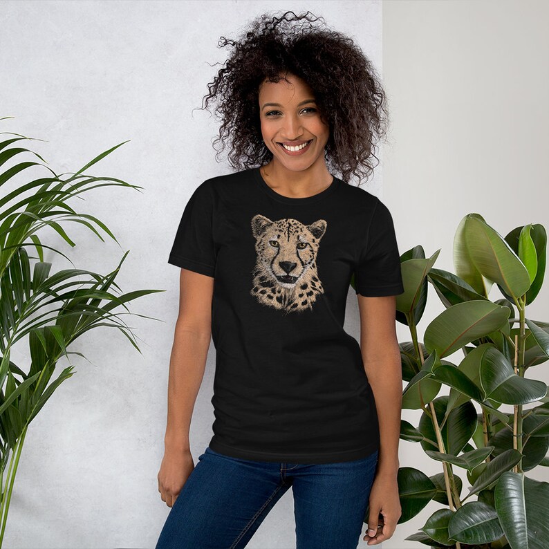 May include: A black t-shirt with a graphic print of a cheetah's face. The cheetah has a brown and black spotted coat.