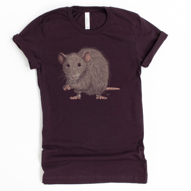 Pode incluir: Uma camiseta roxa escura com um gr&aacute;fico de um rato cinza. O rato est&aacute; em p&eacute; sobre suas patas traseiras e tem as patas dianteiras levantadas.