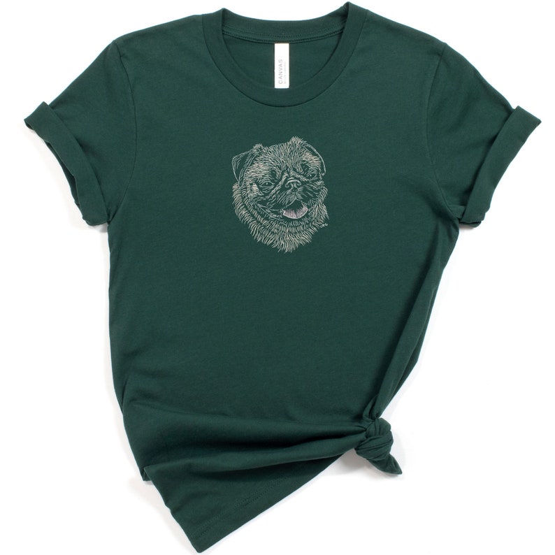 Puede incluir: Una camiseta verde oscuro con un dibujo de l&iacute;nea blanca de la cara de un perro pug en la parte delantera.