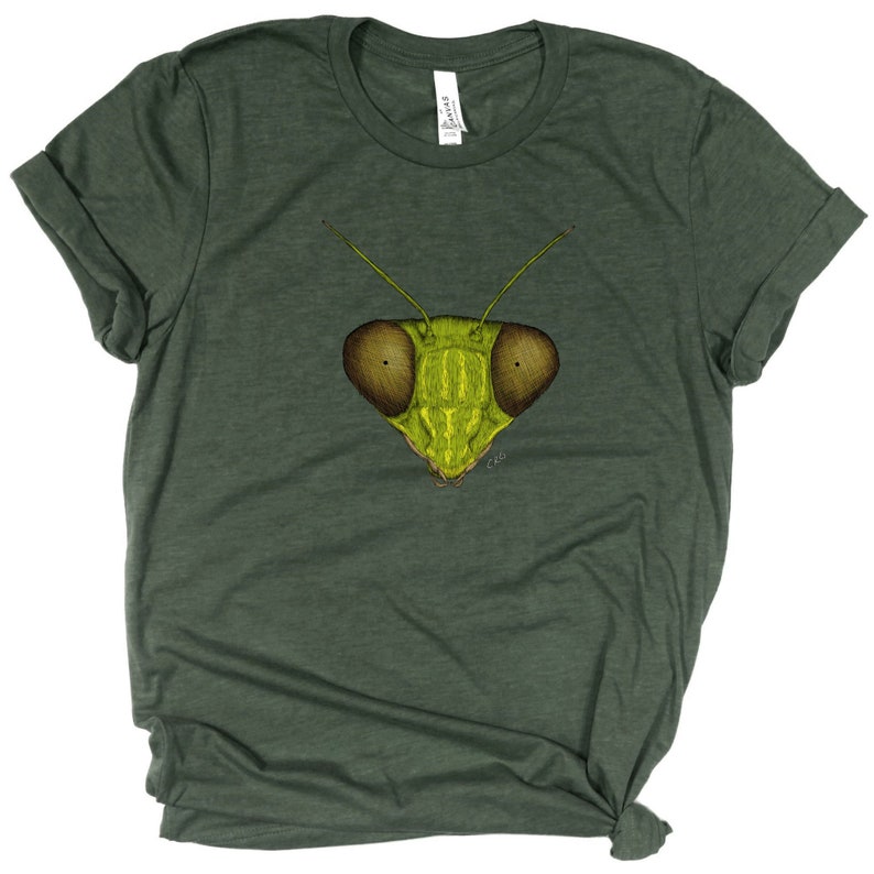 May include: A green t-shirt with a graphic of a praying mantis face on the front. The mantis has large, round eyes and a detailed, textured body.