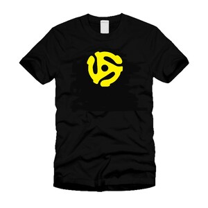 May include: Black t-shirt featuring a bright yellow 45 RPM record adapter graphic. The graphic is centered on the chest. The shirt has a crew neck and short sleeves. A casual, music-themed apparel item.