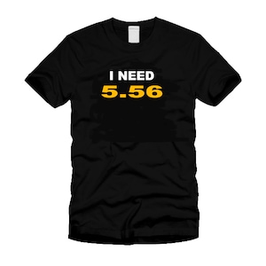 May include: Black t-shirt with the text "I NEED 5.56" in white and yellow. The shirt is a crew neck style and appears to be made of a soft material. The text is centered on the front of the shirt.