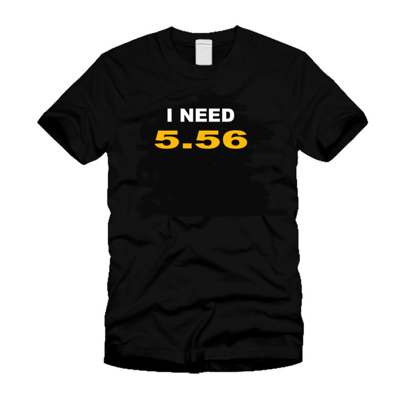 May include: Black t-shirt with the text "I NEED 5.56" in white and yellow. The shirt is a crew neck style and appears to be made of a soft material. The text is centered on the front of the shirt.