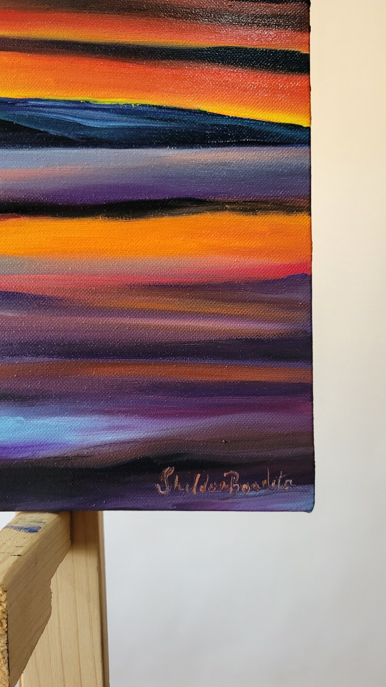 May include: An abstract painting with horizontal bands of color. The artwork features a gradient of colors, including orange, purple, blue, and black. The artist's signature, "Shilda Bondita," is visible in the lower right corner.