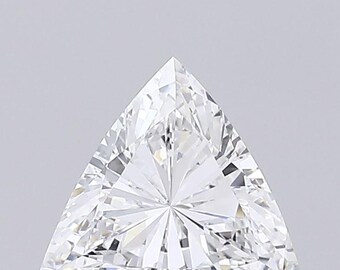 Può includere: Un diamante a taglio brillante a forma triangolare. La gemma ha molte sfaccettature che riflettono la luce, creando un effetto scintillante. Il diamante è posto su uno sfondo grigio chiaro.