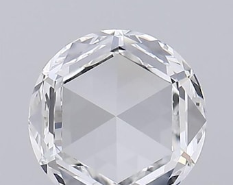 Puede incluir: Un diamante transparente de talla redonda con talla rosa. Las facetas crean un patrón simétrico, reflejando la luz. La gema se encuentra sobre un fondo gris claro, resaltando su claridad y brillo.