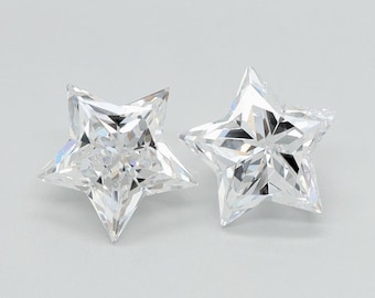 May include: Two clear, star-shaped gemstones with multiple facets, reflecting light. The gemstones are set against a light gray background, showcasing their brilliance and cut. These could be used for jewelry.