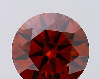 Puede incluir: Una piedra preciosa redonda y roja con un corte facetado. La piedra preciosa tiene un patrón en forma de estrella en el centro.