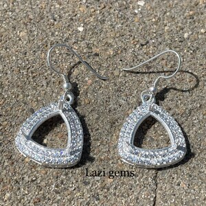 May include: A pair of silver triangle earrings with clear cubic zirconia stones. The earrings have a simple, elegant design and are perfect for everyday wear.