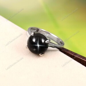 Op de afbeelding: Een zilveren ring met een zwarte stervormige edelsteen. De ring is gezet met vier grijpklauwen en heeft een gepolijste afwerking.