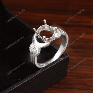 May include: Silver ring with an oval-shaped setting for a gemstone. The ring has a delicate, twisted design.