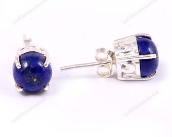 Könnte beinhalten: Ein Paar Ohrstecker mit einem tiefblauen, ovalen Edelstein, der in silberfarbenem Metall gefasst ist. Die Ohrringe haben einen Stecker und einen Butterfly-Verschluss. Die Edelsteine haben eine satte, dunkelblaue Farbe.