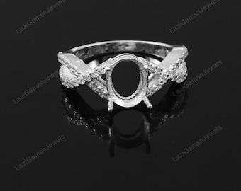 May include: A silver ring with a criss-cross design and a pave setting of small clear stones. The ring has a large oval-shaped setting for a center stone.