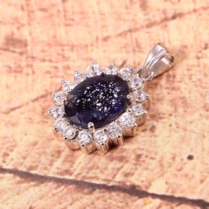 May include: A silver pendant with a blue gemstone surrounded by a halo of smaller white gemstones.