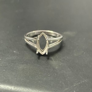 May include: A silver ring with a marquise-shaped setting. The setting is open and ready to hold a gemstone.