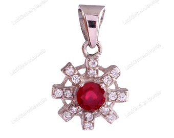 May include: A silver pendant with a red gemstone surrounded by smaller white gemstones. The pendant is shaped like a starburst.