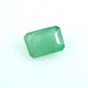 May include: A green emerald gemstone with a rectangular cut.