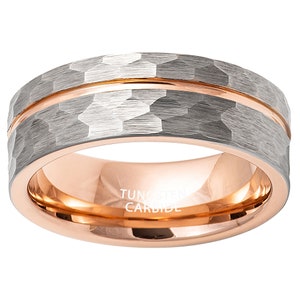 Puede incluir: Un anillo de carburo de tungsteno plateado con una banda de oro rosa y un acabado martillado. El anillo está inscrito con "TUNGSTEN CARBIDE".