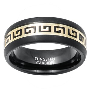 May include: Black tungsten carbide ring with a gold Greek key design. The ring is engraved with the words "Tungsten Carbide".