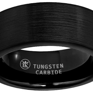 Puede incluir: Un anillo de carburo de tungsteno negro con acabado cepillado. El anillo tiene un borde biselado y está grabado con "TUNGSTEN CARBIDE" y un logotipo de corona.