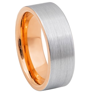Puede incluir: Un anillo de carburo de tungsteno plateado cepillado con una banda interior de oro rosa.