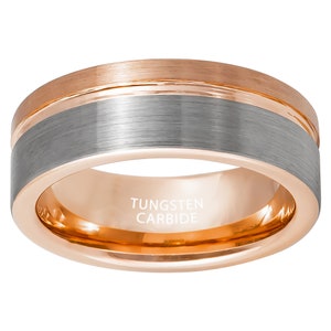 Puede incluir: Un anillo de carburo de tungsteno cepillado plateado con una banda de oro rosa. El anillo está grabado con las palabras "Tungsten Carbide".