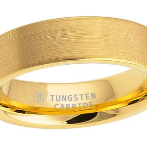 Puede incluir: Un anillo de carburo de tungsteno dorado con acabado cepillado. El anillo tiene un borde biselado y está grabado con "TUNGSTEN CARBIDE".
