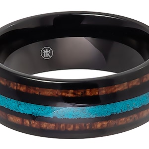 May include: Black tungsten carbide ring with a brown wood inlay and a turquoise blue inlay. The ring has a beveled edge and a polished finish. The ring is engraved with the letters "TK".
