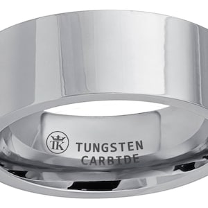 Puede incluir: Un anillo de carburo de tungsteno plateado y pulido. El anillo tiene una banda plana y ancha con una superficie reflectante. El interior del anillo está grabado con el texto "TK TUNGSTEN CARBIDE".