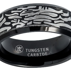 Puede incluir: Anillo de carburo de tungsteno negro con un diseño plateado. El anillo está grabado con "TUNGSTEN CARBIDE" y un logotipo.