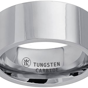 Puede incluir: Un anillo de carburo de tungsteno plateado con un borde biselado y un logotipo que dice "TK" con una corona encima. Las palabras "Tungsten Carbide" están grabadas en el interior del anillo.