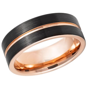 Puede incluir: Un anillo de carburo de tungsteno negro con una incrustación de oro rosa. El anillo tiene un acabado cepillado y un borde biselado.