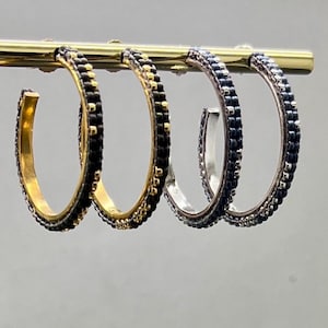 Könnte beinhalten: Drei Paar Creolen mit schwarzen Perlendetails. Die Creolen sind aus Gold, Silber und einer Kombination aus beidem.