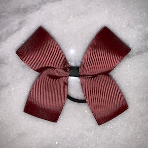 May include: A burgundy bow with a black elastic hair tie.
