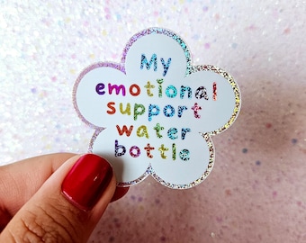 May include: A white flower-shaped sticker with glitter. The sticker says "My emotional support water bottle" in rainbow colors.