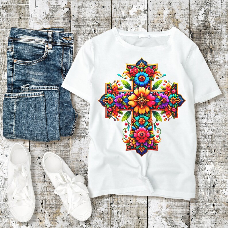May include: White t-shirt with a colorful floral cross design. The cross is made up of flowers in shades of pink, yellow, blue, green, and orange.