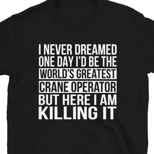 May include: Black t-shirt with white text that reads "I never dreamed one day I'd be the world's greatest crane operator but here I am killing it."