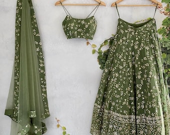 Könnte beinhalten: Ein grüner bestickter Rock und ein passendes Oberteil mit einem durchsichtigen grünen Dupatta. Rock und Oberteil haben ein Blumenmuster mit silbernen Verzierungen.
