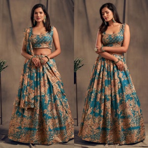 May include: A teal and gold floral print lehenga choli set. The sleeveless top and skirt feature a detailed floral pattern with gold accents. The set includes a matching dupatta. The outfit is suitable for special occasions.