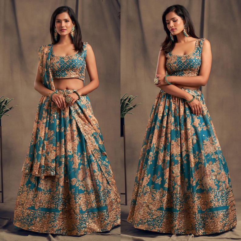 May include: A teal and gold floral print lehenga choli set. The sleeveless top and skirt feature a detailed floral pattern with gold accents. The set includes a matching dupatta. The outfit is suitable for special occasions.