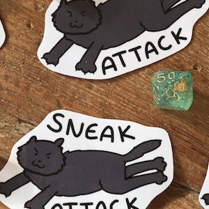 Può includere: Tre adesivi in bianco e nero con un gatto nero di cartone animato con un'espressione birichina. Il gatto è sdraiato a pancia in giù con le zampe allungate. Il testo "Sneak Attack" è scritto sotto il gatto su ogni adesivo.