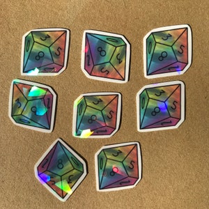 May include: Nine iridescent holographic stickers of a 20-sided die with the numbers 1, 2, 3, 5, 8, 10, 12, and 20.