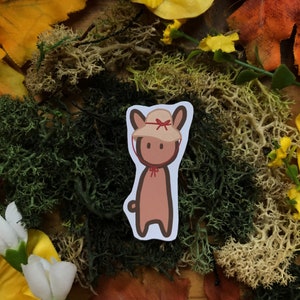 May include: A brown cartoon bunny wearing a red and white sun hat. The bunny is standing on a background of green and brown moss.