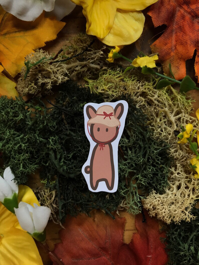 May include: A brown cartoon bunny wearing a red and white sun hat. The bunny is standing on a background of green and brown moss.