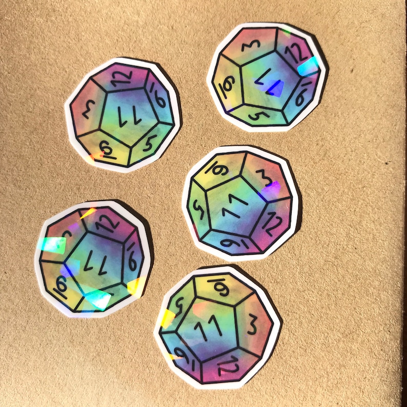 May include: Five iridescent holographic stickers of a 12-sided die with numbers 1 through 12. The stickers are rainbow colored with a white outline.