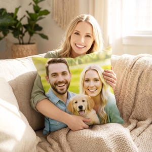 May include: A cushion featuring a smiling couple and a golden retriever puppy. The pillow has a light green and yellow background. The woman in the image is holding the cushion and smiling.